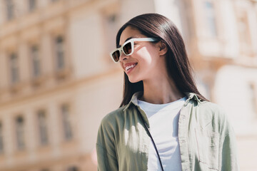 Photo of pretty cheerful girlfriend wear green outfit dark spectacles going shopping enjoying sunny weather outdoors city street