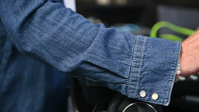 Nahaufnahme eines aktiven DJs in Jeanshemd an elektronischen Turntables auf einer Tanzveranstaltung