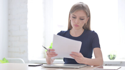 Woman Reading Reports while Sitting in Office