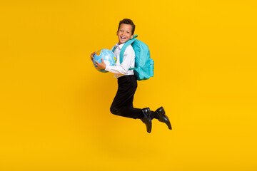 Fototapeta na wymiar Full body portrait of crazy carefree little schoolboy jump hands hold planet earth globe isolated on yellow color background