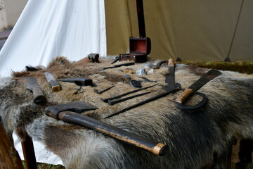 A close up on a set of items put on a boar or wolf hide, including some weapons, axes, swords, a...