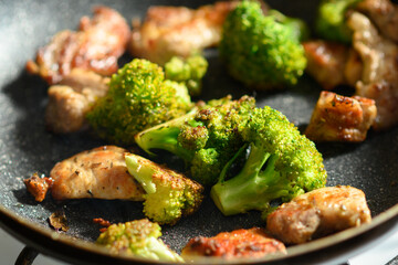 Fried meat and broccoli in a pan close-up.