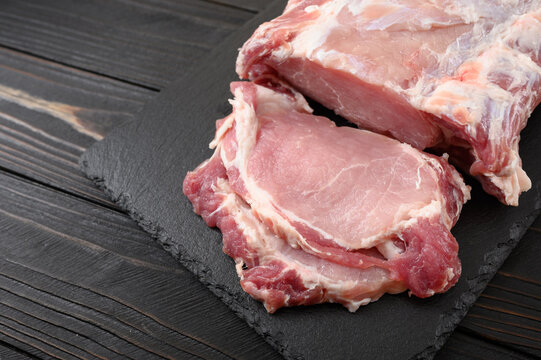 A large piece of pork loin on a rustic dark background.