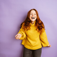 laughing redhead woman with yellow sweater, copyspace with purple background