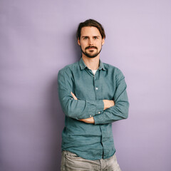 Fototapeta premium serious man with jeans shirt stands with folded arms in front of purple background