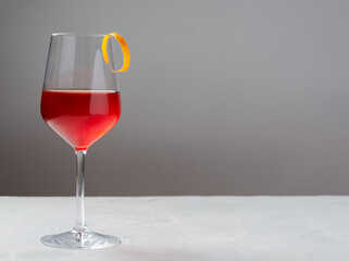 Classic Boulevardier or Cinquecento alcoholic cocktail with campari, rye whiskey and Sweet Vermouth with zest of orange on a grey background
