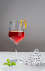 Classic Boulevardier or Cinquecento alcoholic cocktail with campari, rye whiskey and Sweet Vermouth with zest of orange on a grey background