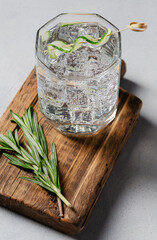 Classic Gin and tonic with cucumber or Tom Collins or Gin Fizz alcoholic cocktail with Gin, tonic, ice, cucumber and rosemary on wood board with background