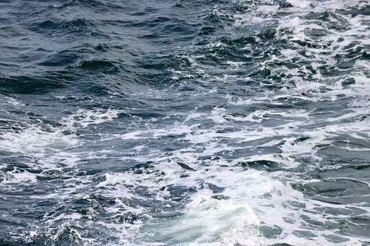Stern waves with white foam tips on greyish blue sea water, photo taken from aboard ship. Selective focus © Ilona Lablaika