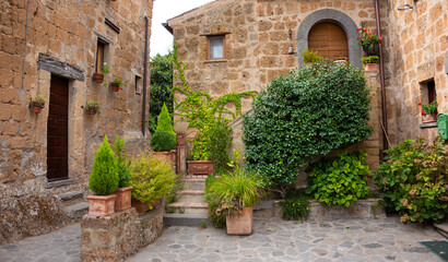 Naklejka na ściany i meble Picturesque courtyard in medieval town in Tuscany, Italy. Old stone walls and plants