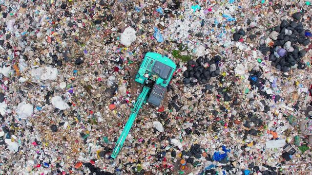 Aerial top drone view of large garbage pile, Excavator machines and garbage truck are working. Consumerism and contamination concept. Ecology problem. 4K
