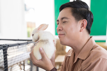 Man playing with pet rabbit at home. Happy young man loves his pet