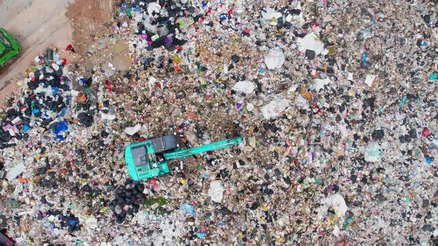Aerial top drone view of large garbage pile, Excavator machines and garbage truck are working. Consumerism and contamination concept. Ecology problem. 4K
