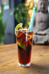Cuba libre long drink. Cuban cocktail with rum, cola, lime and ice cubes, on a wooden table, selective focus.