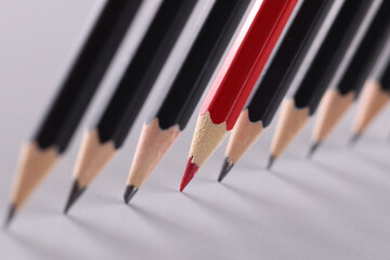 Red pencil separating row of black pencils