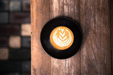 One cup of cappuccino with beautiful latte art on wooden background.