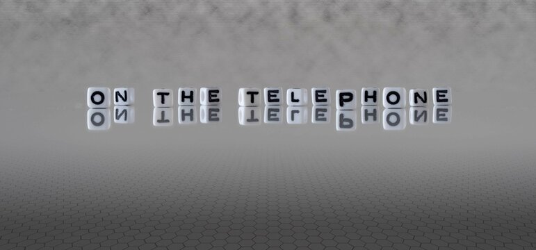 on the telephone word or concept represented by black and white letter cubes on a grey horizon background stretching to infinity