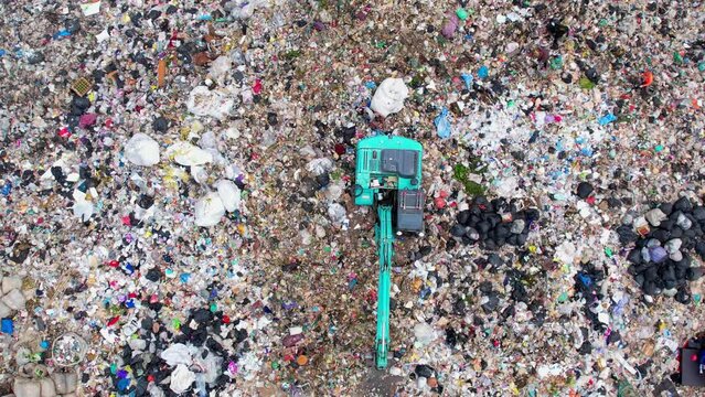 Aerial top drone view of large garbage pile, Excavator machines and garbage truck are working. Consumerism and contamination concept. Ecology problem. 4K
