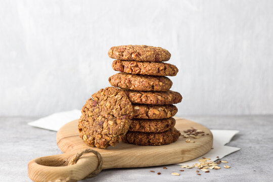 Healthy oatmeal cookies with dates, nuts and flaxseed on a wooden board on a gray textured background. Delicious homemade vegan food