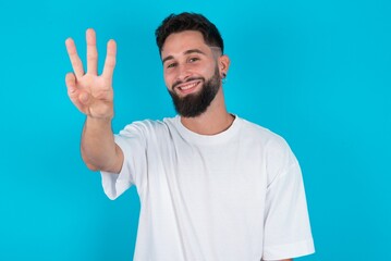Fototapeta premium bearded caucasian man wearing white T-shirt over blue background showing and pointing up with fingers number three while smiling confident and happy.