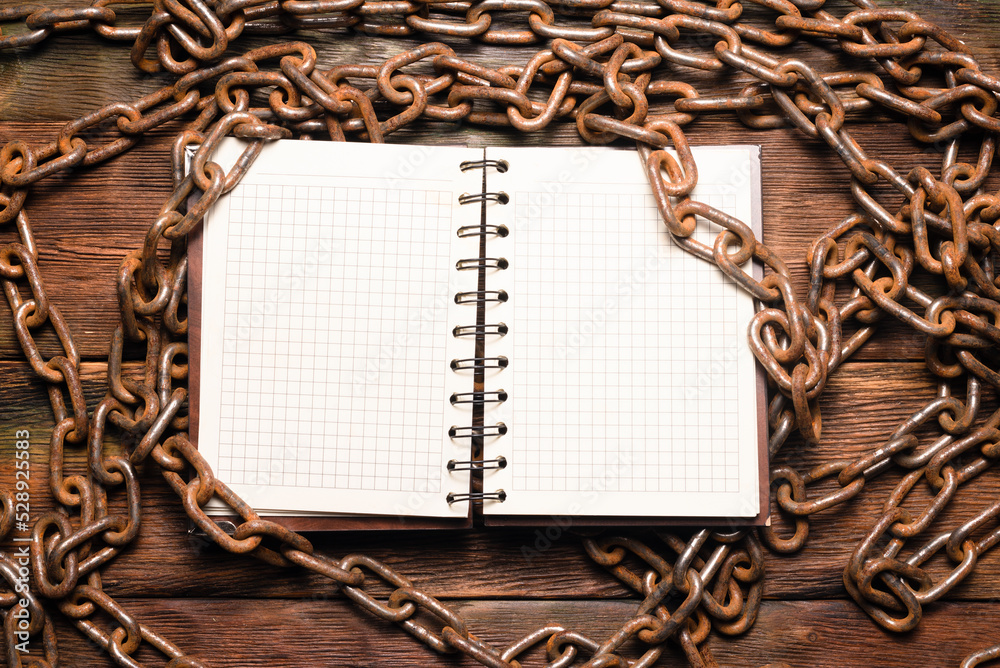 Wall mural open blank page notebook with copy space and old rusty iron chain on the wooden table background. to