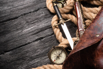 Pirate concept background. Musket gun, dagger, compass, pirate captain hat and mooring rope on the...