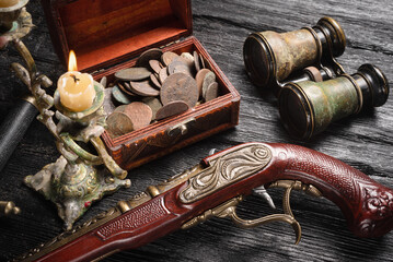  Pirate concept background. Treasure chest with coins, musket gun, dagger and binoculars on black...