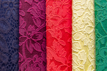 Samples of colored brocade fabrics in selective focus. A large assortment of high-quality and fashionable fabrics, a choice of textiles in the fabric store.