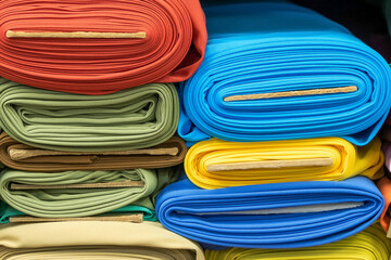 Rolls of bright multi-colored fabric on a shelf in a store. Sale of fashion fabrics for clothing.