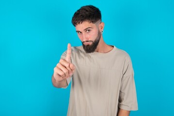 bearded caucasian man wearing casual T-shirt over blue background frustrated and pointing to the front