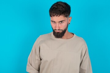 Fototapeta premium bearded caucasian man wearing casual T-shirt over blue background Pointing down with fingers showing advertisement, surprised face and open mouth