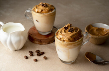 Dalgona coffee in glass cups, coffee beans. Moody neutral, warm backgroung with copy space