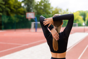 Back view of fit woman warming up outdoors, Fitness woman doing stretch exercise stretching her arms