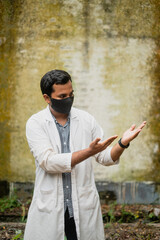 South asian young doctor showing something , Bangladeshi medical student isolated wearing apron and mask, professionals showing warning signs 