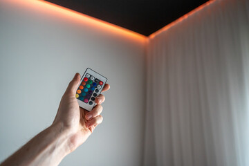 Hand holding led lighting remote control with light turned on ceiling
