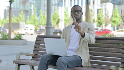 Rejecting African Man in Denial While using Laptop Sitting Outdoor on Bench