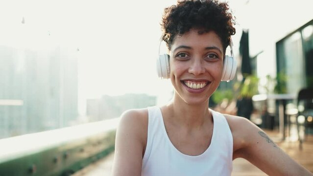 Smiling young African sporty woman in headphones looking at the camera outdoors