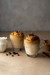 Dalgona coffee in glass cups, coffee beans. Moody neutral, warm backgroung with copy space