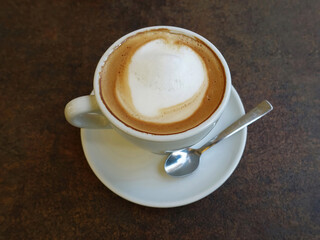 Cup of coffee with teaspoon on the table