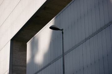 Metal street lamp against a gray blue wall in an urban urban space. Street lighting in the daytime....