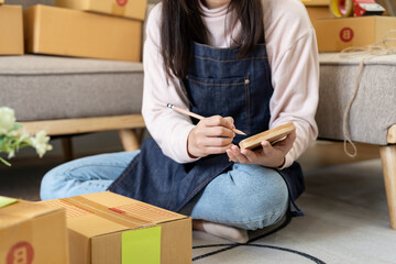 Shipping shopping online ,young start up small business owner writing address on cardboard box at workplace.small business entrepreneur SME or freelance asian woman working with box at home