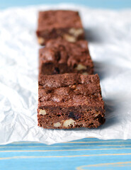 Chocolate homemade brownies with dried cranberries and walnuts on the blue wooden background. 