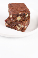 Chocolate homemade brownies with dried cranberries and walnuts on the white  plate. Copy space for text