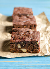 Chocolate homemade brownies with dried cranberries and walnuts on the blue wooden background