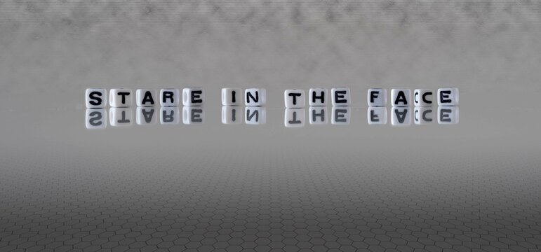 stare in the face word or concept represented by black and white letter cubes on a grey horizon background stretching to infinity