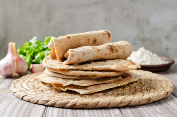 Homemade Chapati Roti Flatbread with greens and garlic on grey background. Freshly baked indian street food