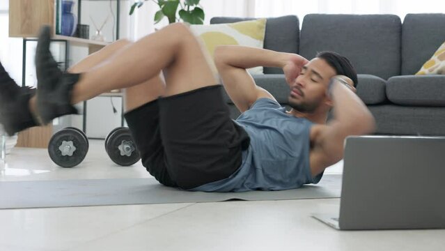 Fitness man, home workout and laptop while watching online exercise tutorial in the living room at home. Fit and active man doing crunches for abs while using internet for a health and wellness blog