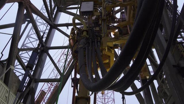 Drilling platform. Topdrive with wires goes up. Assembly line process. Pipes connections.