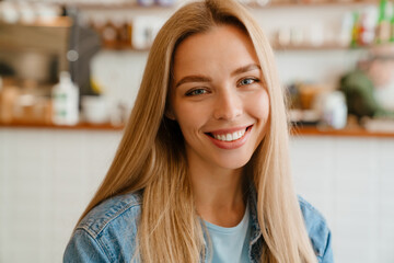 White blonde woman wearing shirt smiling while sitting in cafe