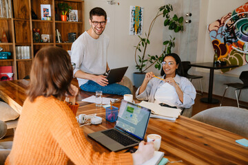 Multiracial young colleagues discussing project while working in office